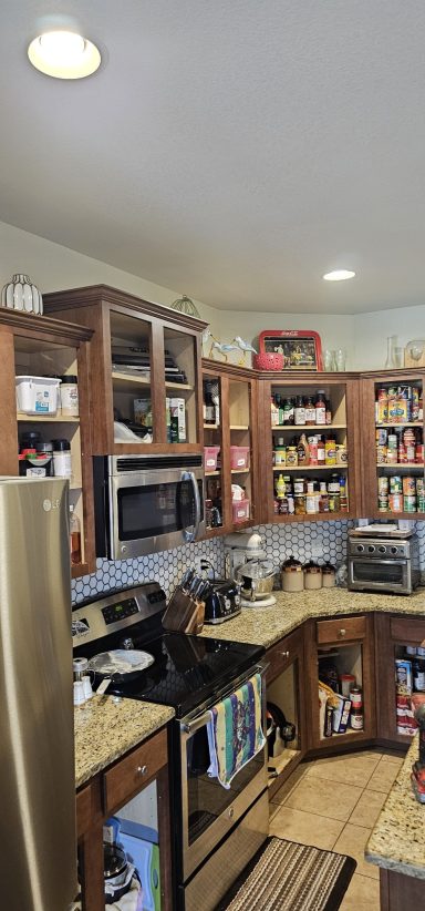 Cozy kitchen with wooden cabinets, stainless steel appliances, and various food items.
